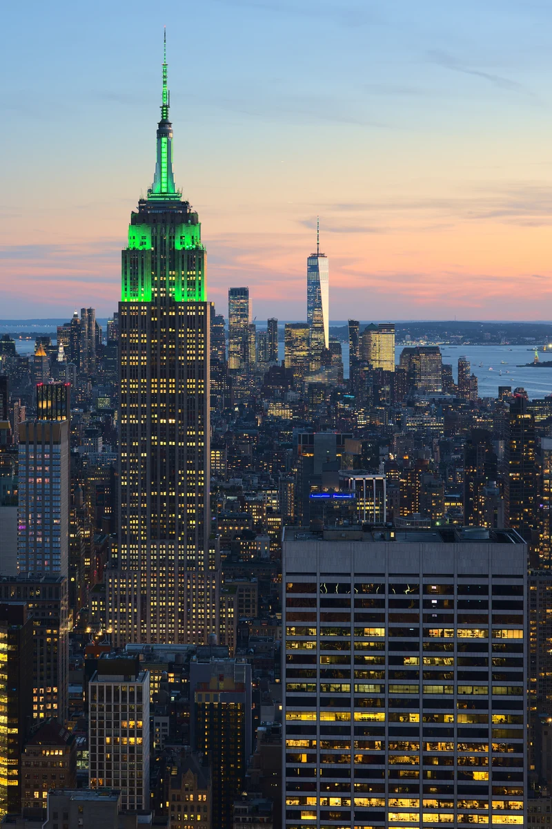 Grün beleuchtetes Empire State Building in New York bei Sonnenuntergang