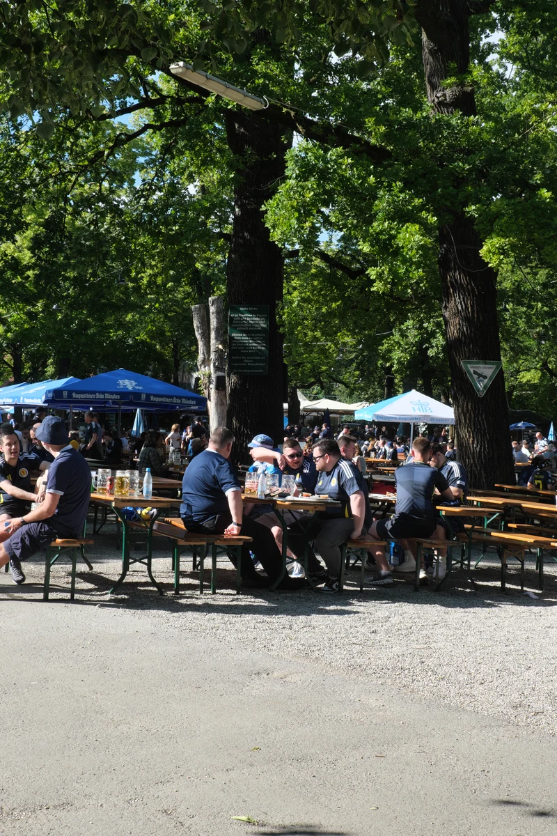 Biergarten Hirschgarten in München mit Gästen an langen Holztischen