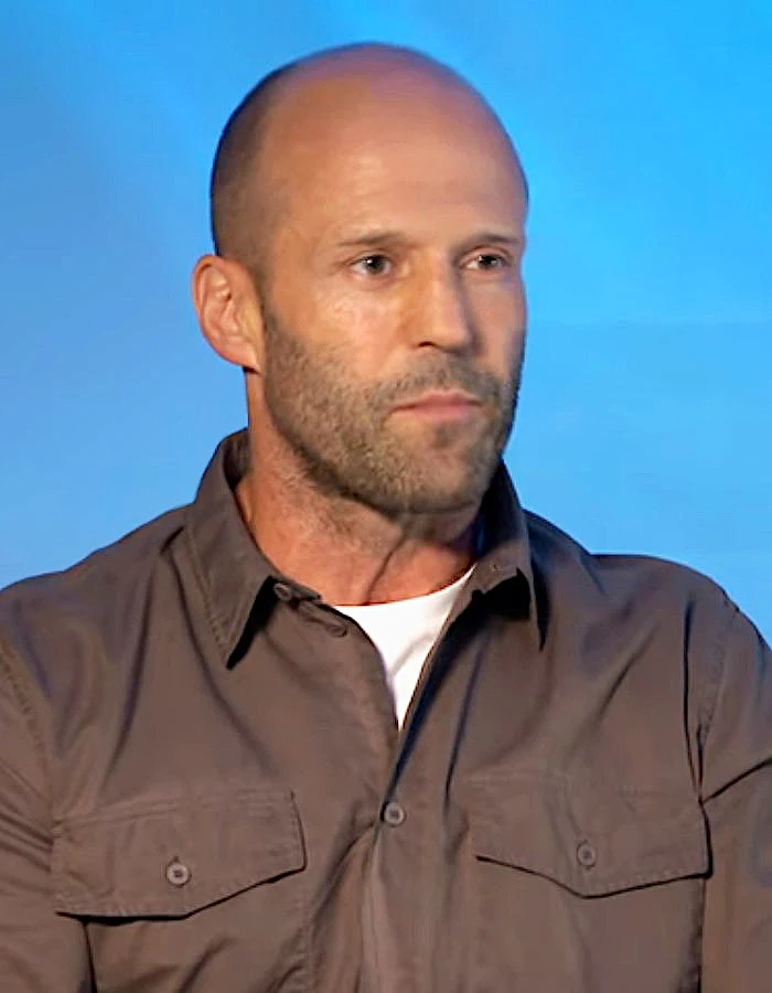 Jason Statham bei einem Interview vor blauem Hintergrund