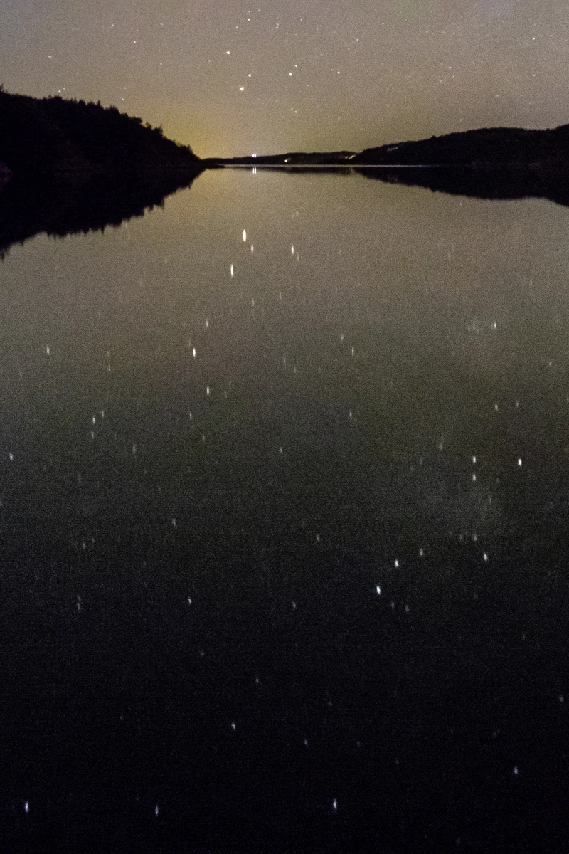 Sternenhimmel über dem Wasser eines Fjords bei Nacht