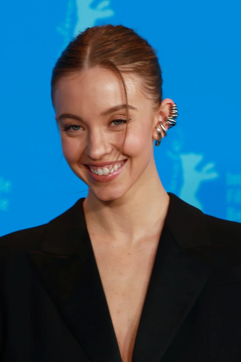 Sydney Sweeney lächelnd im schwarzen Blazer vor der blauen Berlinale-Pressewand bei der Berlinale 2023