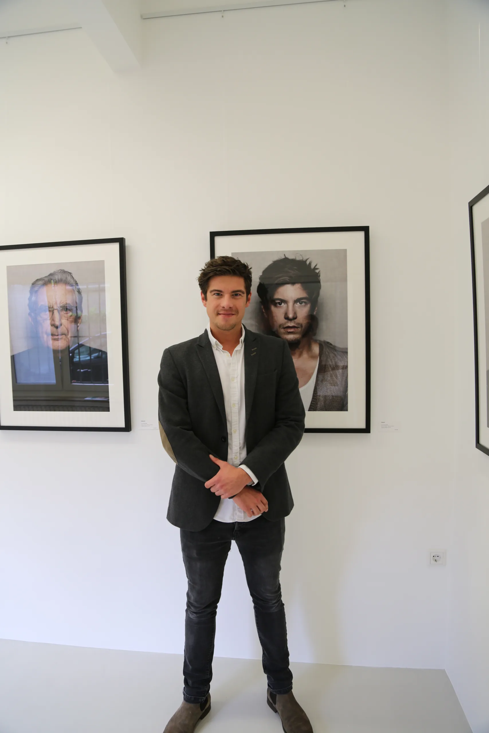 Philipp Danne in einer Galerie vor gerahmten Porträts