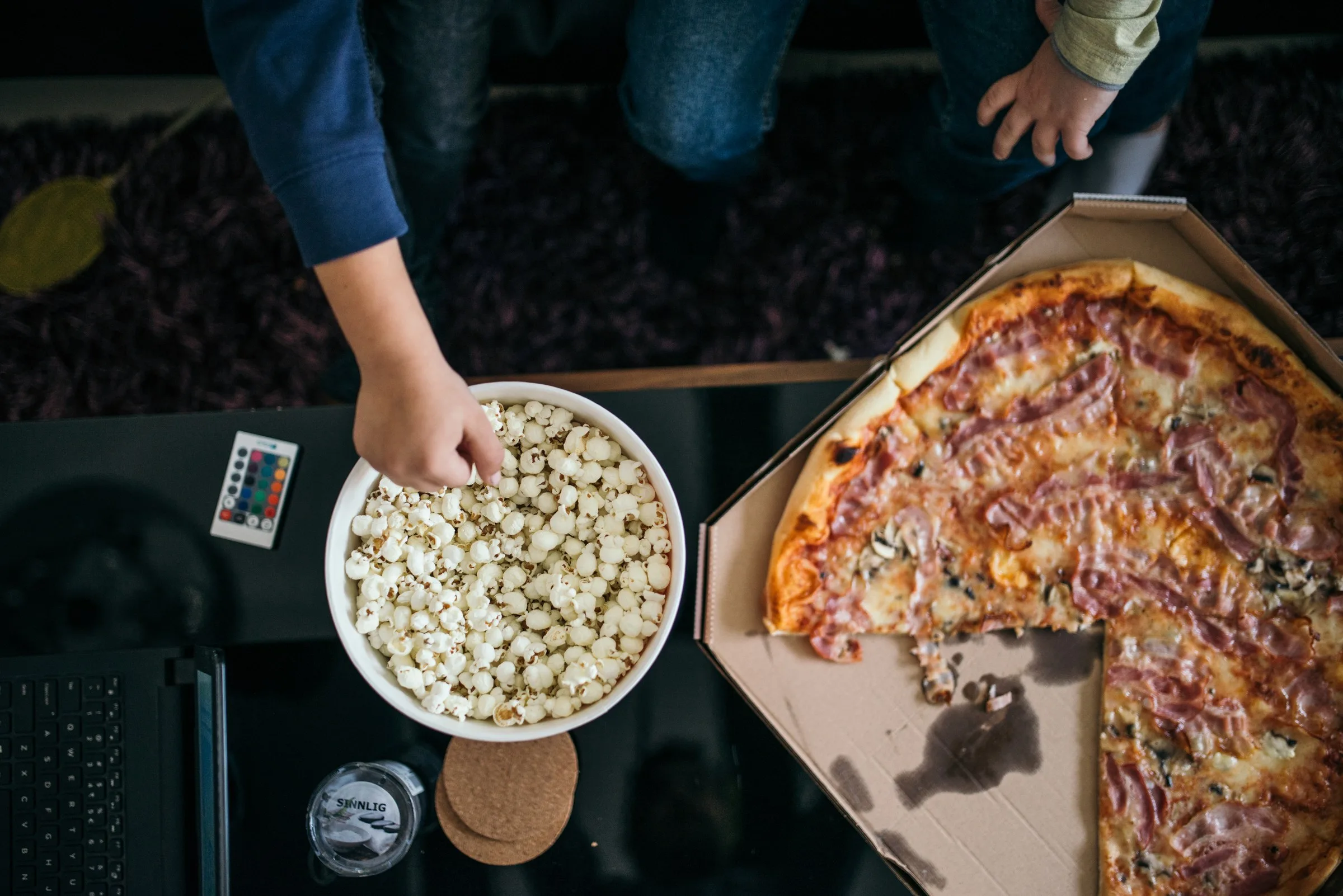 Pizza, Popcorn und Fernbedienung bei einem Filmabend zu Hause