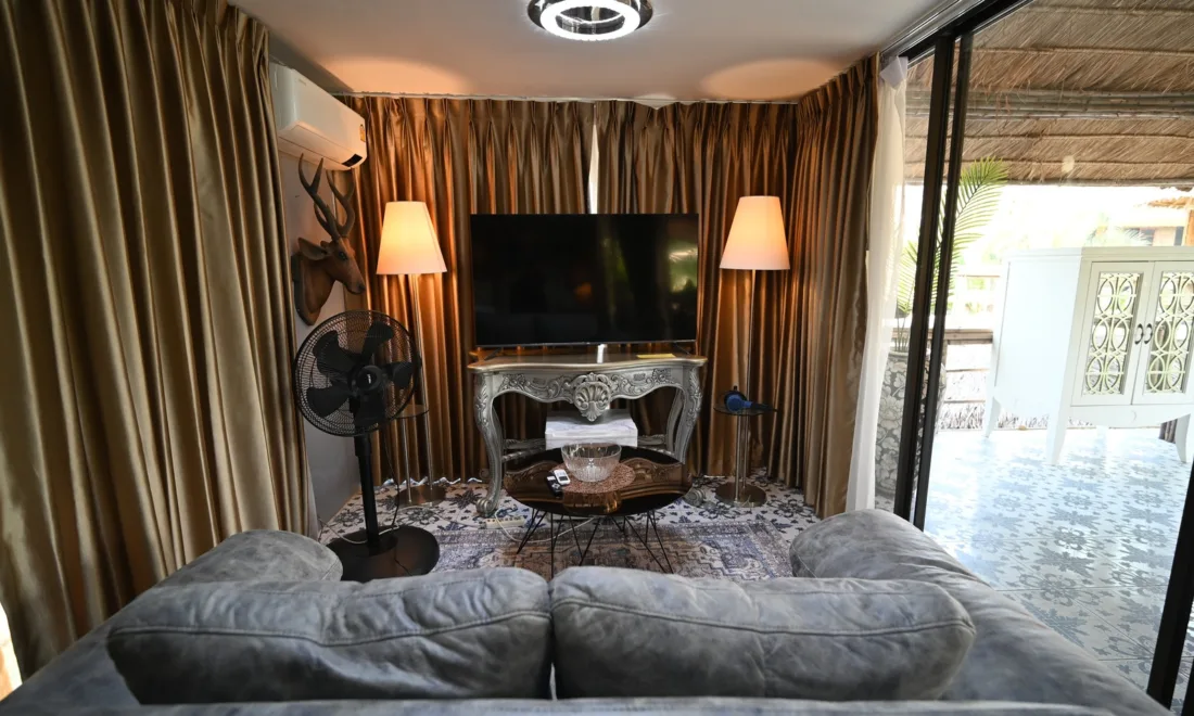 Ein gemütliches Wohnzimmer mit großem Flachbildfernseher auf einer Konsole und grauem Sofa