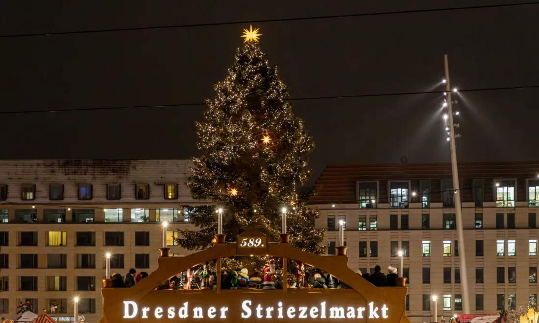Weihnachtsmarkt in Dresden mit beleuchtetem Eingang und Weihnachtspyramide in der Dämmerung