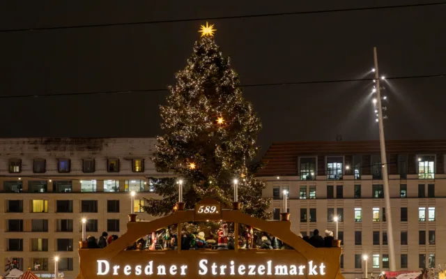 Weihnachtsmarkt in Dresden mit beleuchtetem Eingang und Weihnachtspyramide in der Dämmerung